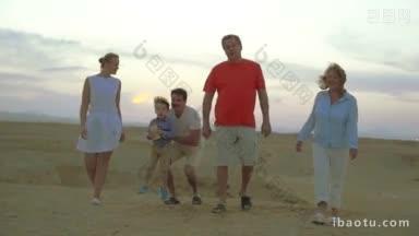 慢<strong>动作</strong>斯坦尼康拍摄的一个家庭晚上走在海滩上快乐的父母，祖父母和孩子坐在爸爸