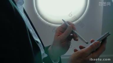 一个商人在飞行中在飞机上用钢笔在智能<strong>手机</strong>上打字的特写镜头