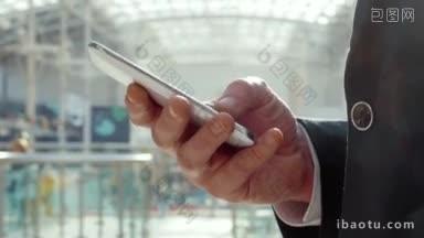 一个年轻的商人在现代化的办公楼或购物中心用智能手机打短信的特写镜头