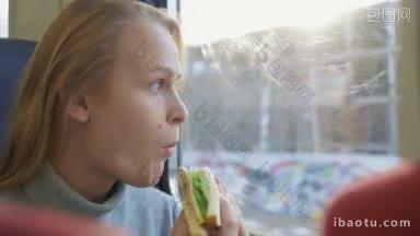年轻女子在火车上咬了一口，看着窗外，她吃着三明治和新鲜的沙拉和