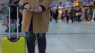站在机场或火车站，手里拿着平板<strong>电脑的</strong>女子正拿着手推车
