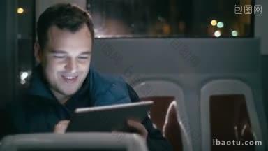 年轻的微笑的男子使用触摸板在每天晚上乘坐公共汽车在城市娱乐旅行