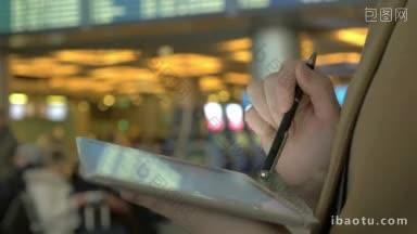 一个女人站在机场用钢笔在平板电脑上<strong>打字</strong>的<strong>特写</strong>镜头