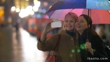 在雨中的城市，两个快乐的女人在彩色雨伞下用<strong>手机</strong>自拍