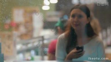 一名年轻女子独自坐在咖啡馆里，<strong>用手机</strong>输入短信或在社交媒体上交流