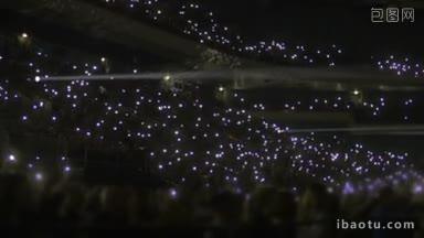 晚上在体育场表演时，看台上的人群拿着小手电筒挥手