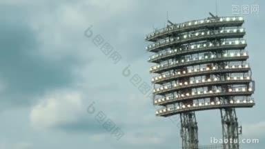 大型体育场的灯光在夜晚多云的天空照明塔的背景下打开