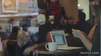 <strong>两个</strong>朋友坐在咖啡馆里聊天，女人拿着智能手机和笔记本<strong>电脑</strong>
