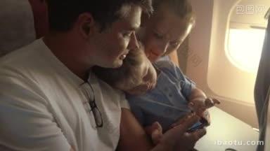 年轻的父母和小儿子乘飞机旅行，孩子在父亲的智能<strong>手机</strong>上玩游戏自娱自乐