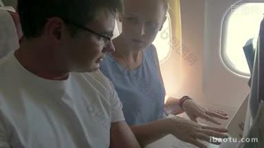 一个男人和一个女人坐在飞机上用笔记本电脑讨论<strong>业务</strong>，女人在打字