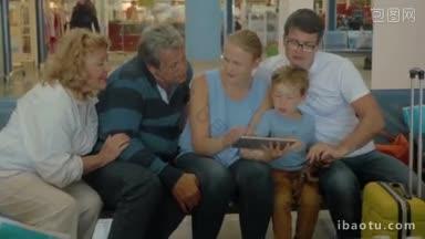 一个大家庭的成员们坐在候<strong>诊室</strong>里用平板电脑看假期的照片