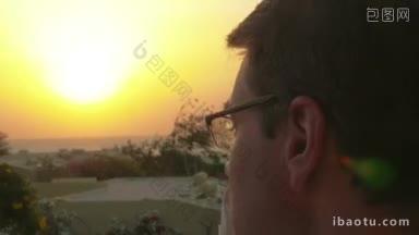 一名男子戴上眼镜，在度假胜地观看美丽的日落