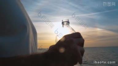 慢动作斯坦尼康和特写镜头，一个年轻人在海边喝<strong>塑料瓶</strong>水在日落