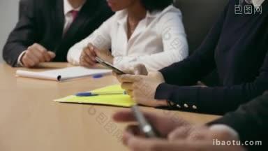 一群商务人士在公司会议室开会，一位女士正在<strong>用手机</strong>输入信息和电子邮件