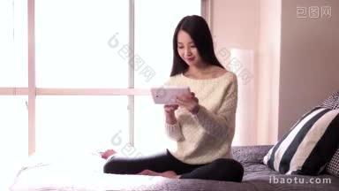 美丽的年轻亚洲女子放松在家里的<strong>卧室</strong>和微笑的漂亮的日本<strong>女孩</strong>使用iPad数字平板电脑上网