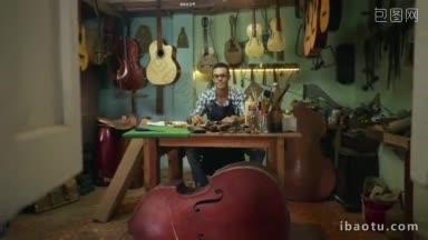 琵琶制作店和原声乐器画像一个年轻的成年工匠坐在他的办公桌前微笑