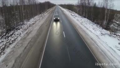 飞过的黑色汽车在北领地的道路上行驶，周围是雪原和光秃秃的树木