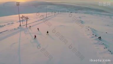 航拍的两<strong>名</strong>滑雪者和两<strong>名</strong>单板滑雪者在夕阳下的雪原和远处的山丘上滑下雪道
