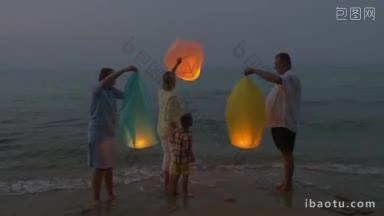 一家人，妈妈，孩子和爷爷奶奶晚上在海边放纸灯笼