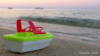 塑料玩具船是站在沙滩上的海浪来了，在日落，海浪冲走了它