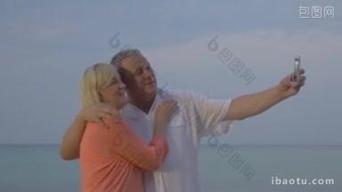 快乐的老夫妇在度假时用智能<strong>手机</strong>照片在大海背景下互相拥抱自拍