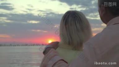 背影的一对成熟的夫妇看着美丽的自然景色的日落仍海妇女享受日落