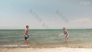 年轻快乐的男女在<strong>海边玩</strong>得很开心，他们用放在海里的球拍打网球