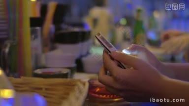 一个女人在吧台用智能手机打字的特写镜头