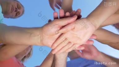 低角度的镜头，人们把手放在一起，举起<strong>他们</strong>的团队合作概念