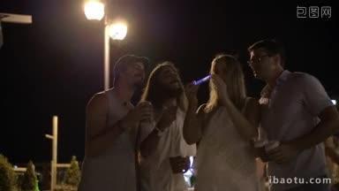 四个快乐的朋友夜游时在街上用智能手机自拍的慢镜头