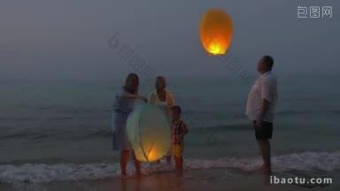 幸福的家庭在夜晚站在海边，放飞天灯，每个人都在向它招手