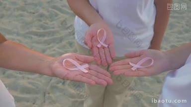 三名妇女手里拿着粉色的乳腺癌<strong>宣传</strong>丝带，支持和声援抗击疾病