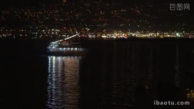 小型照明旅游船航行在夜晚的<strong>海上</strong>明亮和彩色灯光的海滨城市的背景