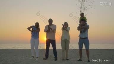 慢镜头，快乐的父母和祖父母制作五彩纸屑<strong>烟花爆竹</strong>在海岸上，在日落小男孩坐在