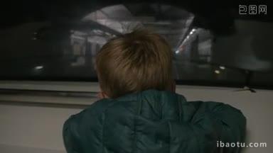 慢镜头:一个穿着夹克<strong>的</strong>小男孩透过地铁到达车站<strong>的</strong>窗户往外看