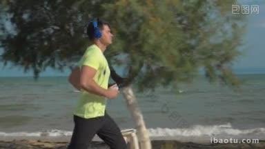 慢动作斯坦尼康拍摄的一个年轻人沿着空旷的海滩跑步，他听着耳机的<strong>音乐</strong>
