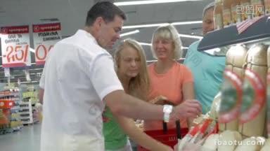 四个面带微笑的朋友站在超市的<strong>货架</strong>旁挑选商品，讨论着