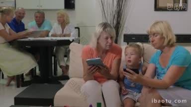 奶奶和孙子在家里，一个女人在给孩子看手机上的东西，另一个在用平板电脑