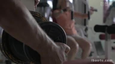 特写镜头的男子固定额外的重量磁盘上的杠铃妇女训练的运动机器上的背景