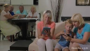 两个奶奶和小孙子在家里一个女人和一个男孩玩智能手机，另一个奶奶和