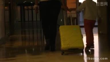 在机场候机楼，母亲和儿子一起推着行李箱走着
