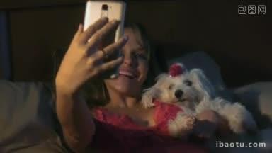 人和<strong>宠物</strong>年轻女子在晚上用手机自拍肖像