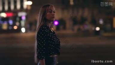 夜晚，在城市的背景和城市的灯光下，一个年轻的女人独自漫步在城市的街道上