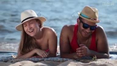 特写的有吸引力的夫妇在<strong>帽子</strong>和太阳镜躺在<strong>沙滩</strong>上，在夏天的一天夫妇享受乐趣