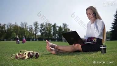 漂亮的金发女商人坐在绿色的草地上赤脚在公园的草坪上接电话