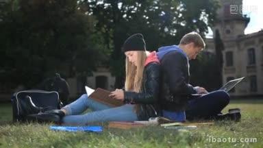 在校园附近一起学习的大学生夫妇背对背坐在草地上学习