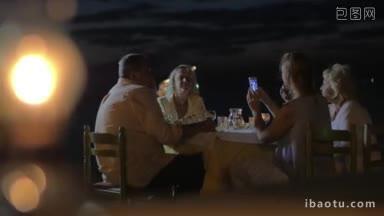 傍晚，一家人坐在海边的餐桌旁，在希腊的城市里吃晚餐