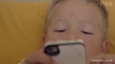 小男孩在黄色背景的智能手机上<strong>玩游戏</strong>的特写镜头
