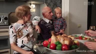 快乐的家庭与祖父母坐在节日的餐桌上在感恩节在家里可爱的孙女穿着天使的衣服端豌豆
