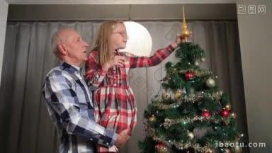 爷爷抱着他的孙女把主要的<strong>装饰</strong>玩具放在圣诞树上可爱的小女孩帮助<strong>圣诞节</strong>